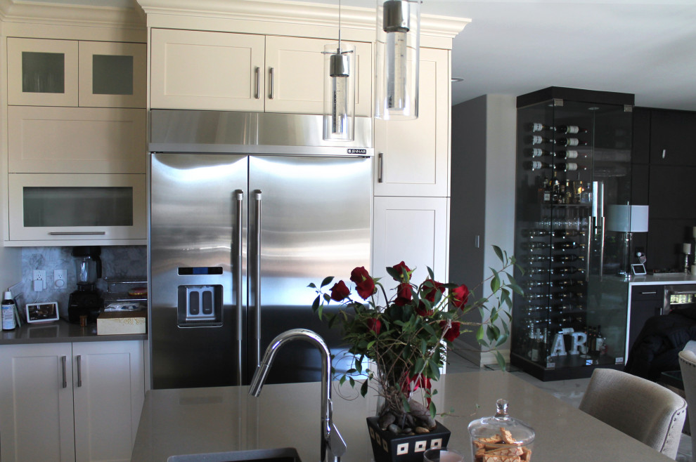 Large transitional u-shaped eat-in kitchen photo with shaker cabinets, white cabinets, quartz countertops, gray backsplash, stainless steel appliances, an island and gray countertops