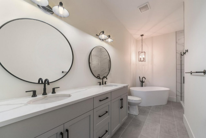 Medium sized traditional ensuite bathroom in Vancouver with shaker cabinets, grey cabinets, a freestanding bath, a corner shower, a two-piece toilet, multi-coloured tiles, stone tiles, white walls, porcelain flooring, a submerged sink, engineered stone worktops, beige floors, a hinged door, beige worktops, double sinks and a built in vanity unit.