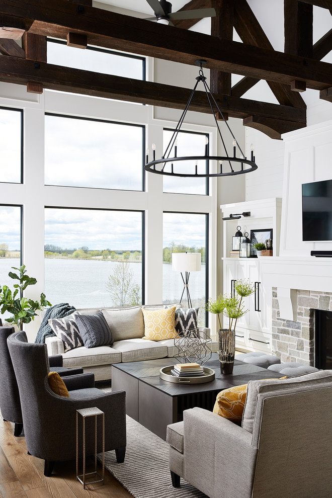 Inspiration for a large transitional open concept living room in Minneapolis with grey walls, medium hardwood floors, a standard fireplace, a stone fireplace surround, a wall-mounted tv and brown floor.