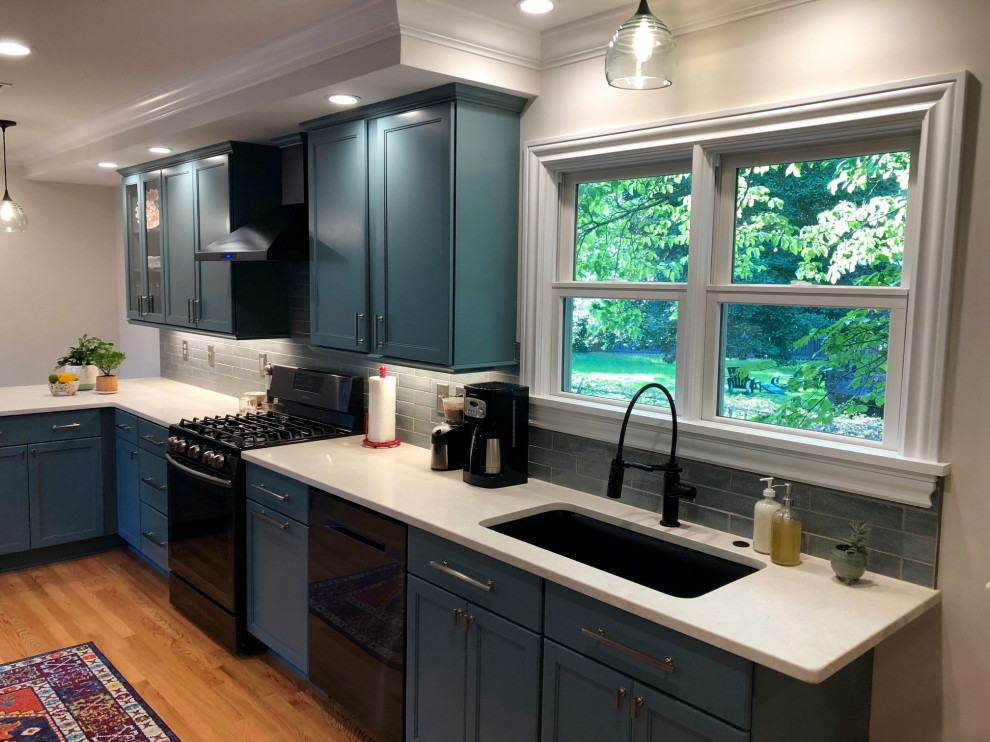 This is an example of a contemporary u-shaped separate kitchen in Raleigh with a single-bowl sink, flat-panel cabinets, green cabinets, quartzite benchtops, green splashback, cement tile splashback, black appliances, light hardwood floors, no island and white benchtop.