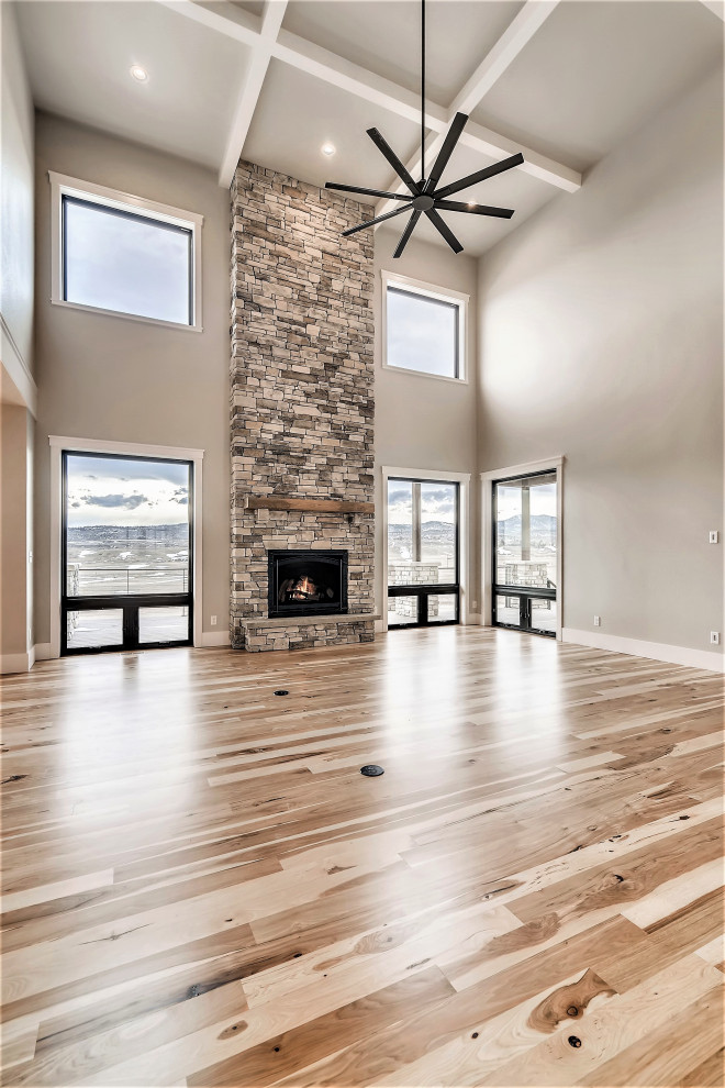 Großes, Repräsentatives Landhausstil Wohnzimmer im Loft-Stil mit grauer Wandfarbe, Teppichboden, Kamin, Kaminumrandung aus gestapelten Steinen, TV-Wand, grauem Boden und Kassettendecke in Denver