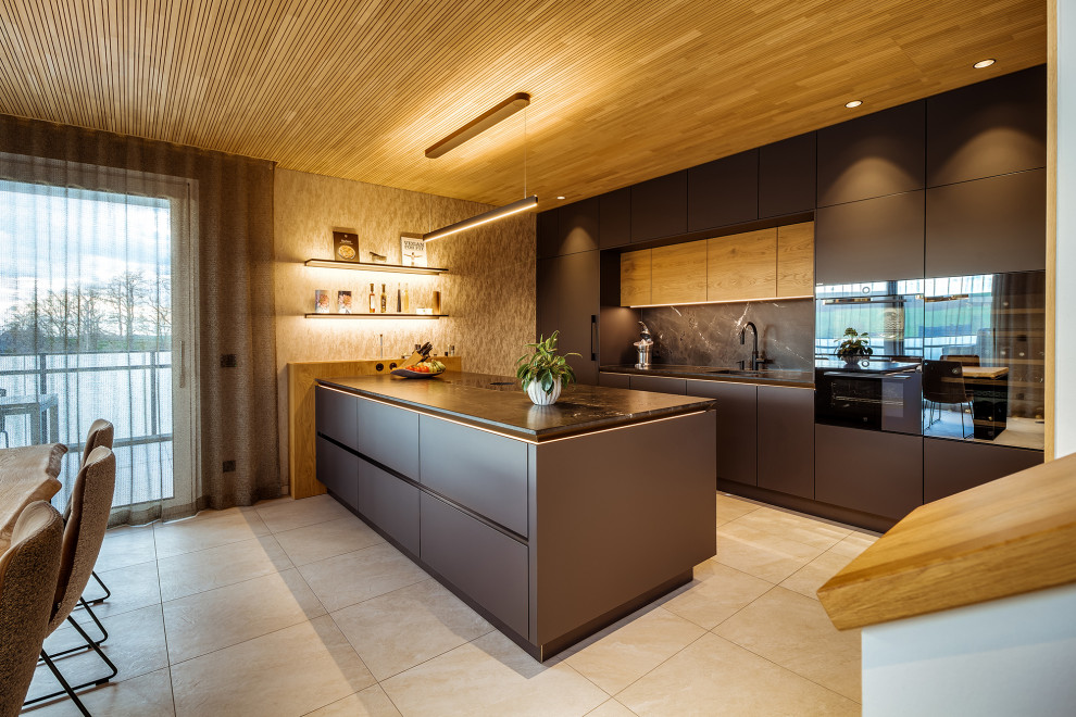 Zweizeilige Moderne Küche mit Unterbauwaschbecken, flächenbündigen Schrankfronten, braunen Schränken, Küchenrückwand in Schwarz, Rückwand aus Stein, schwarzen Elektrogeräten, Halbinsel, beigem Boden, schwarzer Arbeitsplatte und Holzdecke in Dresden