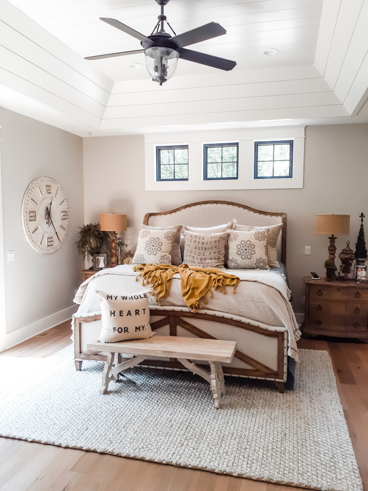 Foto på ett sovrum, med grå väggar, mellanmörkt trägolv och brunt golv