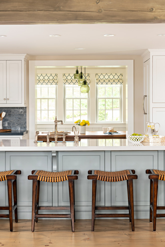 Beach style kitchen in Boston with recessed-panel cabinets, white cabinets, grey splashback, light hardwood floors, with island, beige floor and white benchtop.