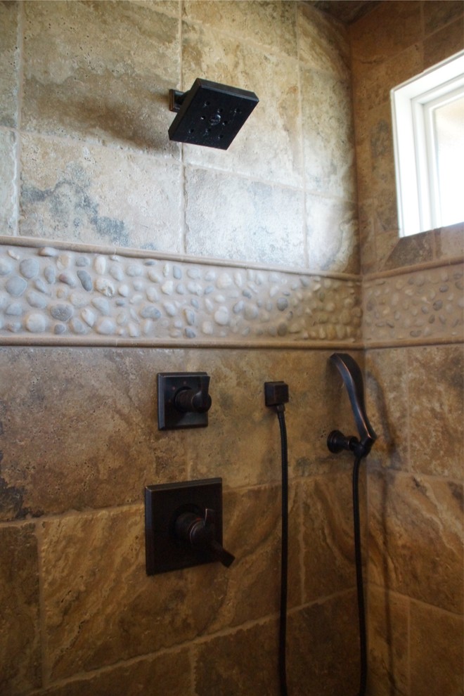 Example of a mid-sized mountain style master multicolored tile and stone tile travertine floor alcove shower design with raised-panel cabinets, medium tone wood cabinets, a one-piece toilet, beige walls, an undermount sink and granite countertops