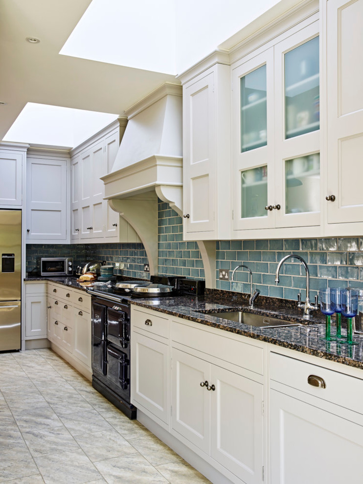 Inspiration for a mid-sized country eat-in kitchen in London with a farmhouse sink, shaker cabinets, granite benchtops, blue splashback, ceramic splashback, stainless steel appliances and with island.