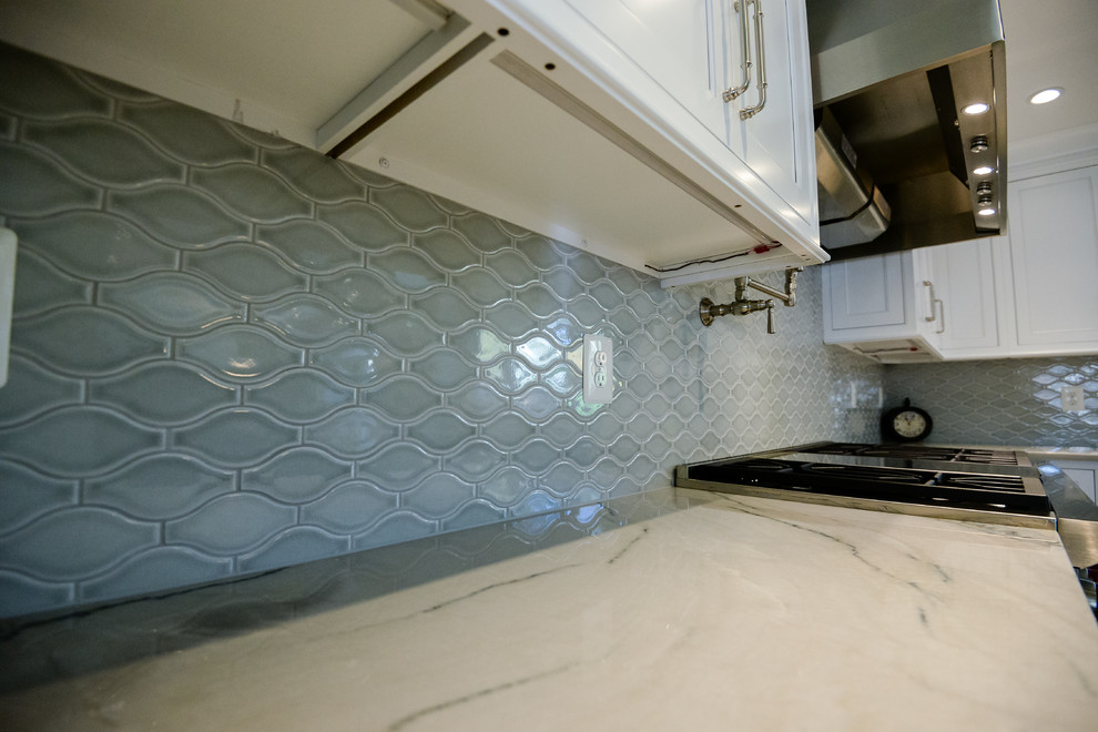 Example of a large transitional u-shaped medium tone wood floor and brown floor eat-in kitchen design in DC Metro with a farmhouse sink, recessed-panel cabinets, white cabinets, marble countertops, stainless steel appliances, an island, gray backsplash and porcelain backsplash