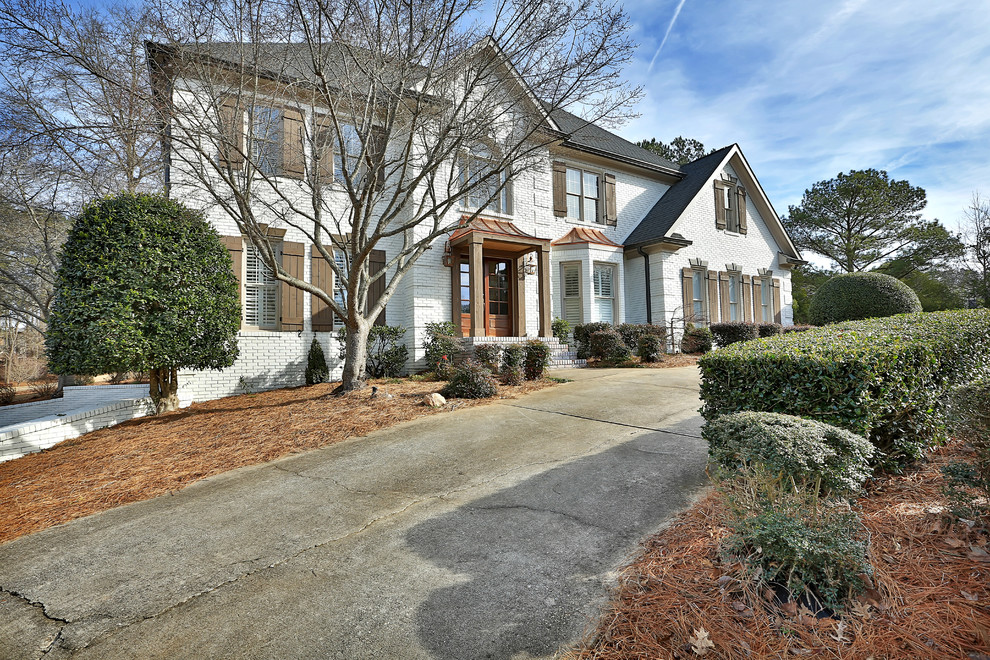 Photo of a mid-sized traditional two-storey brick white house exterior in Atlanta with a hip roof and a shingle roof.