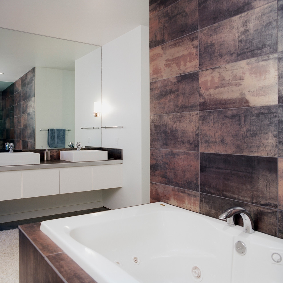 Photo of a contemporary master bathroom in Kansas City with flat-panel cabinets, white cabinets, black tile, white walls, concrete floors, a vessel sink, tile benchtops, a drop-in tub, porcelain tile and beige floor.