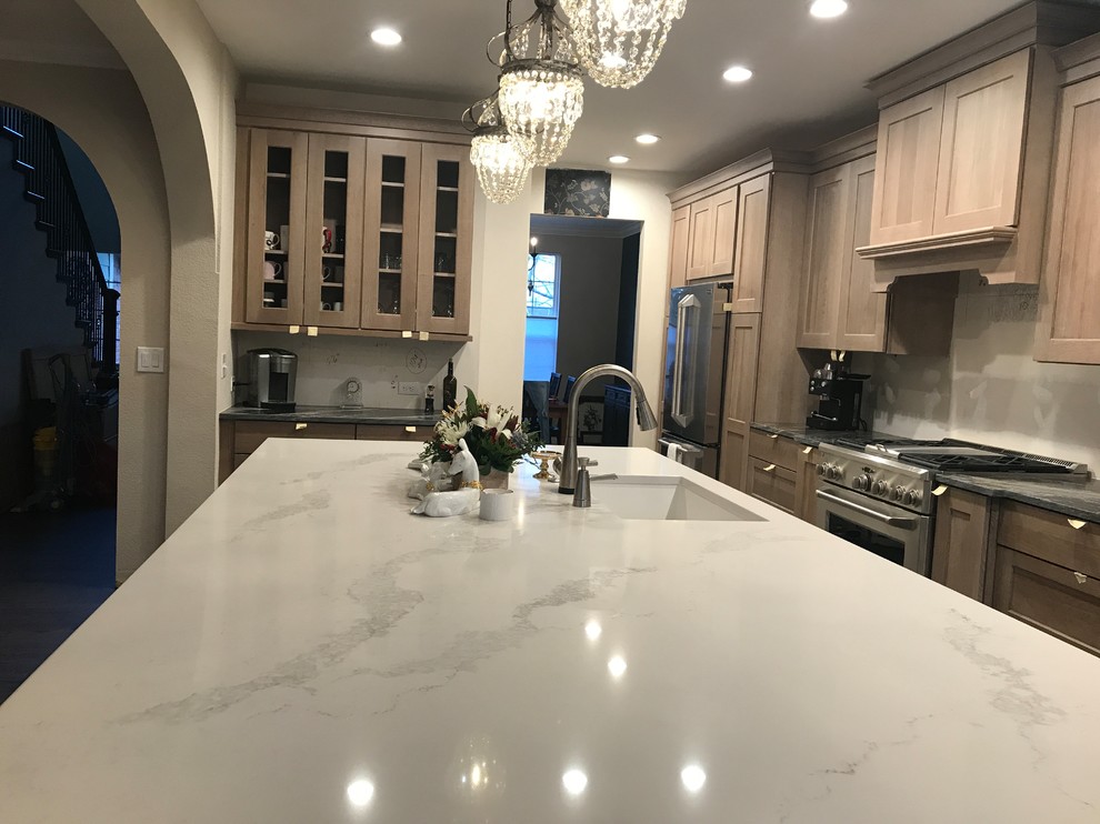 This is an example of a large contemporary l-shaped kitchen pantry in Denver with an undermount sink, shaker cabinets, quartz benchtops, stainless steel appliances, vinyl floors, with island, white benchtop and vaulted.