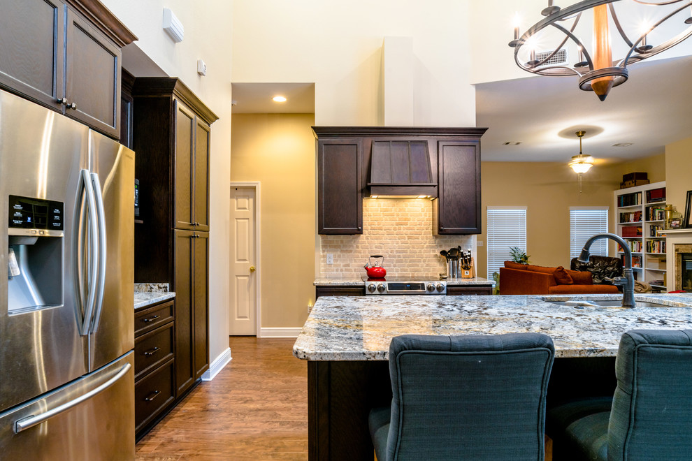Large transitional l-shaped vinyl floor eat-in kitchen photo in Miami with an undermount sink, shaker cabinets, dark wood cabinets, granite countertops, beige backsplash, porcelain backsplash, stainless steel appliances and an island