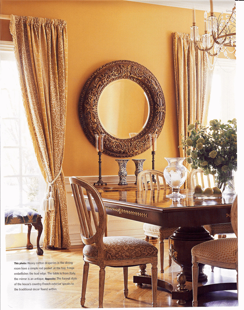 Elegant dining room photo in New York with orange walls