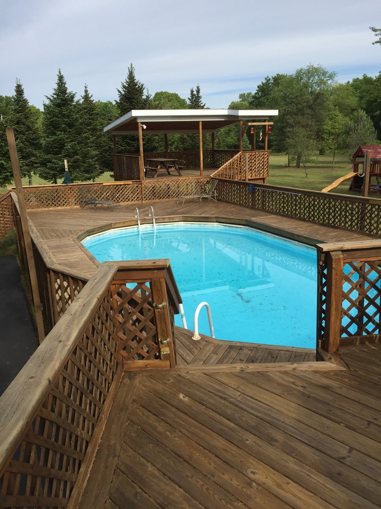 Large side yard custom-shaped aboveground pool in Grand Rapids with decking.