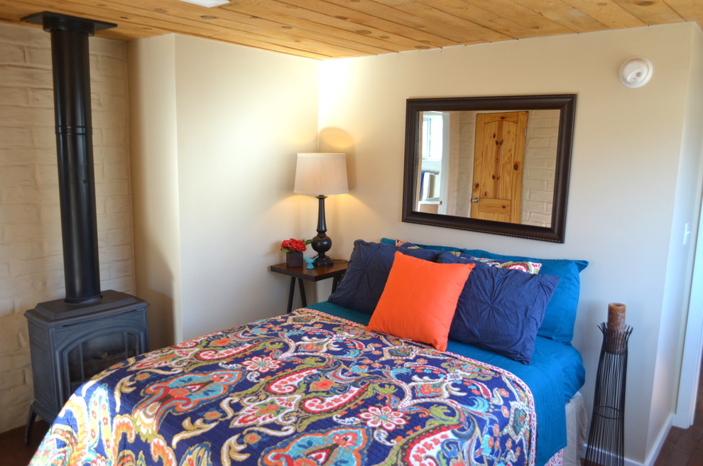 Design ideas for a mid-sized master bedroom in Albuquerque with white walls, brick floors and a wood stove.