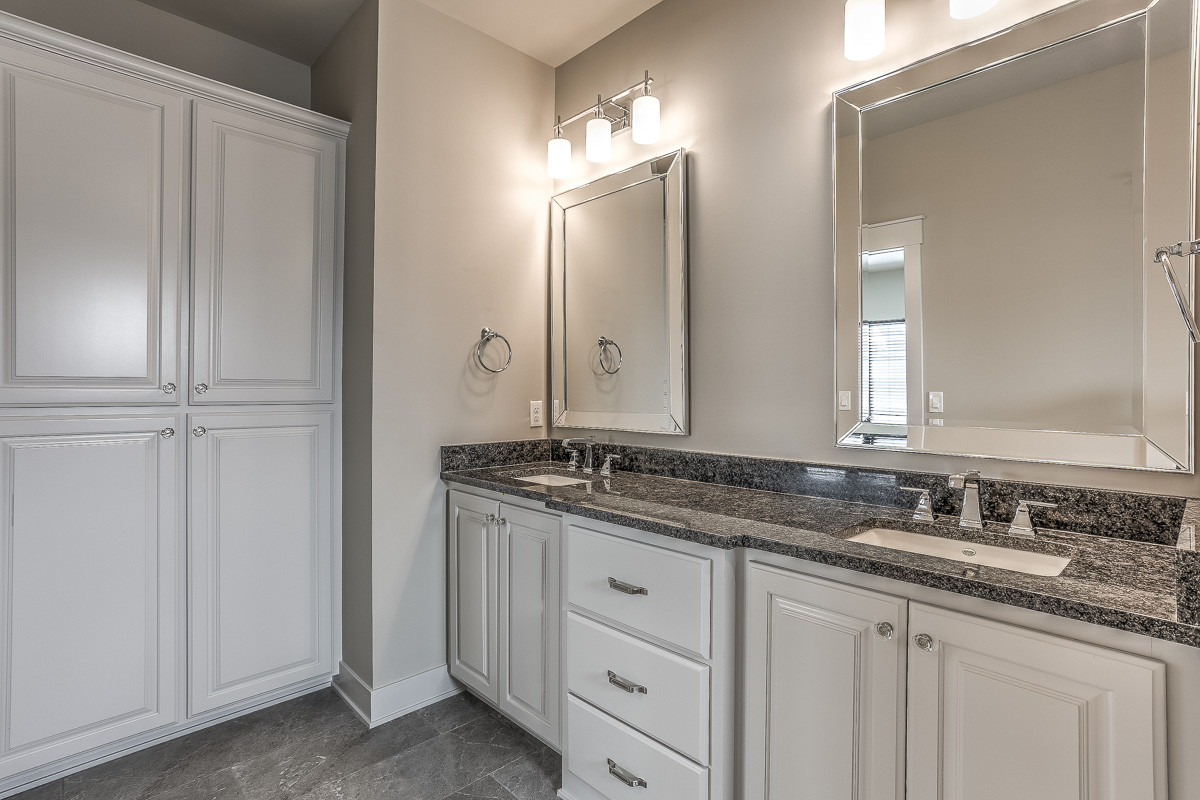Example of a farmhouse master gray tile ceramic tile and gray floor doorless shower design in Omaha with raised-panel cabinets, white cabinets, a two-piece toilet, gray walls, an undermount sink, gran