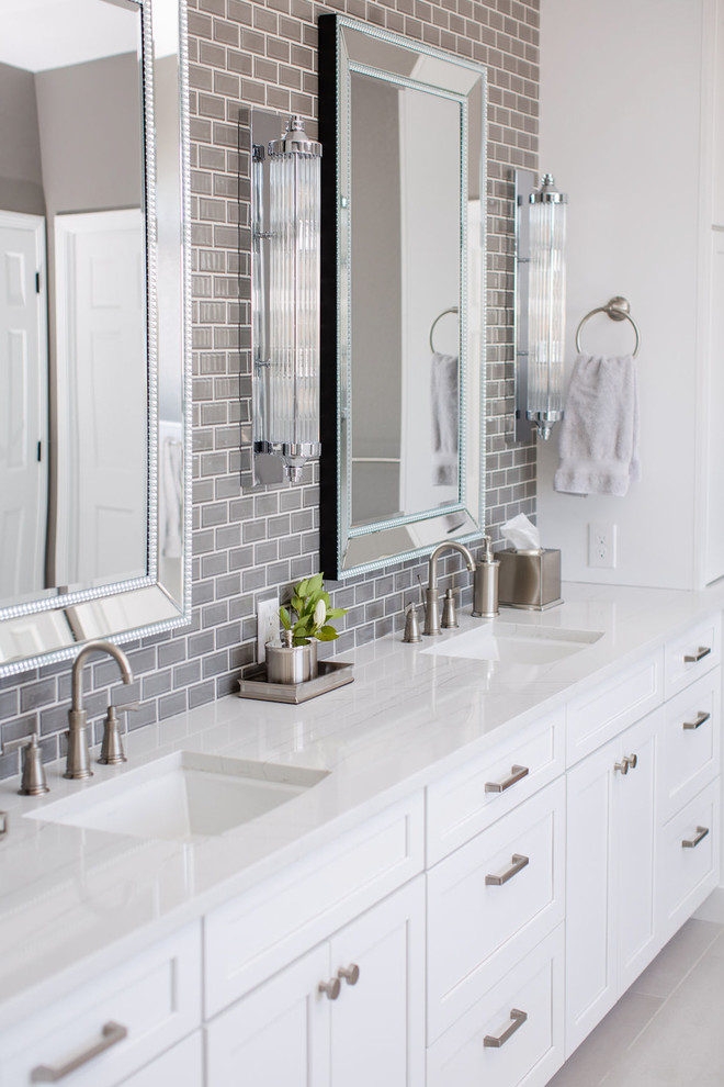 Photo of an expansive transitional master bathroom in Denver with shaker cabinets, white cabinets, a freestanding tub, a corner shower, a one-piece toilet, white tile, ceramic tile, grey walls, porcelain floors, an undermount sink, engineered quartz benchtops, grey floor, a hinged shower door and white benchtops.