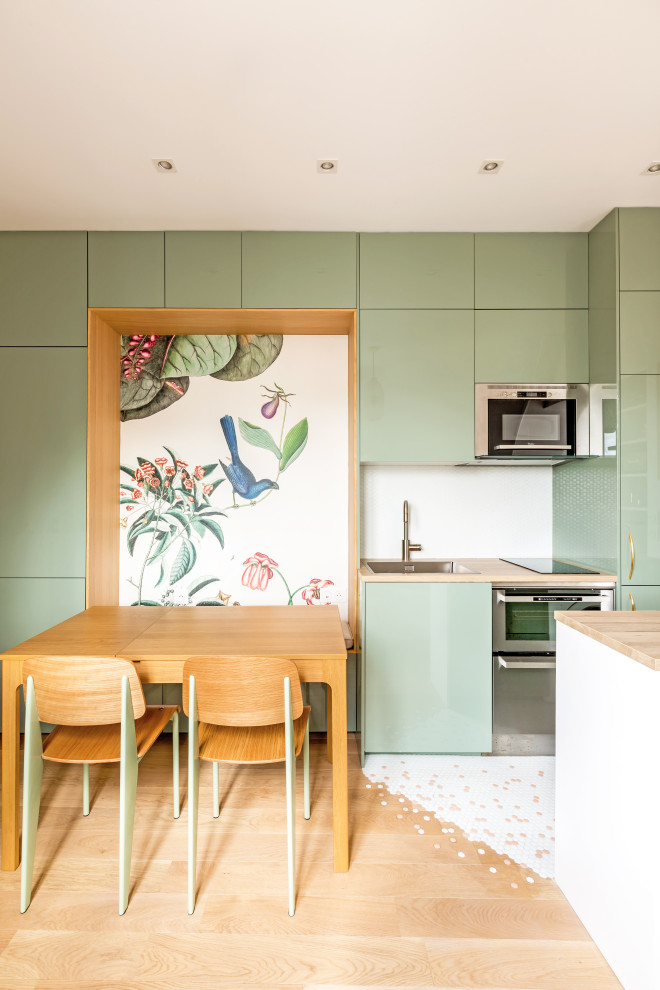 Photo of a mid-sized traditional single-wall open plan kitchen in Paris with an undermount sink, beaded inset cabinets, green cabinets, laminate benchtops, white splashback, mosaic tile splashback, stainless steel appliances, light hardwood floors, with island, brown floor and brown benchtop.