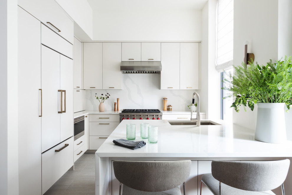 Example of a mid-sized trendy u-shaped porcelain tile and gray floor enclosed kitchen design in New York with an undermount sink, flat-panel cabinets, gray cabinets, quartz countertops, white backsplash, quartz backsplash, paneled appliances, an island and white countertops