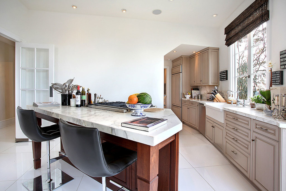 This is an example of a mid-sized contemporary kitchen in Los Angeles with raised-panel cabinets, beige cabinets, marble benchtops, white splashback, panelled appliances and with island.