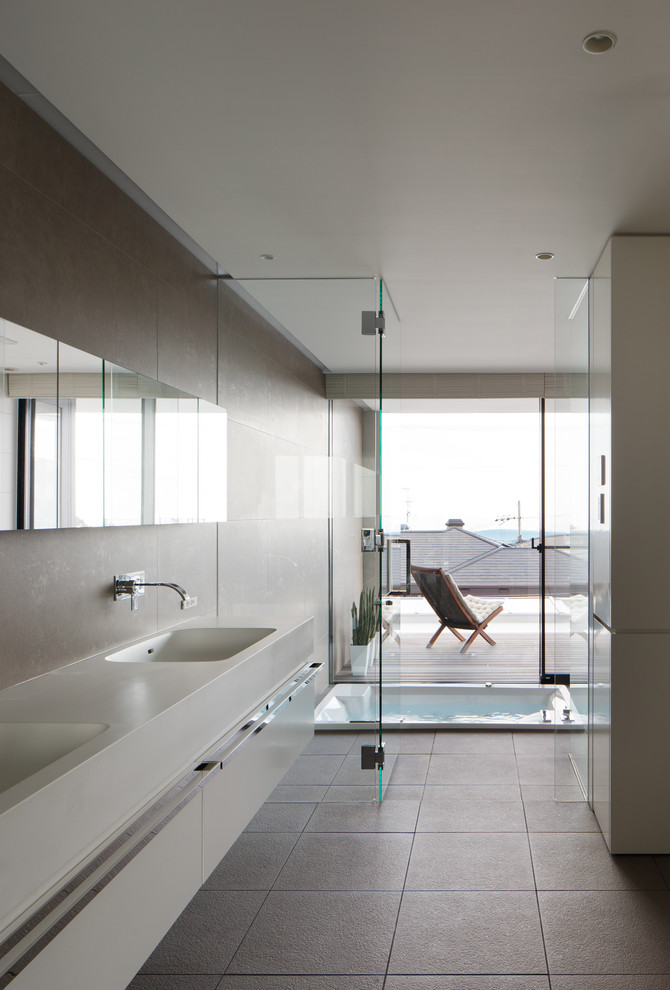 Photo of a modern bathroom in Kobe with flat-panel cabinets, an integrated sink, a drop-in tub, beige walls, ceramic floors and beige floor.