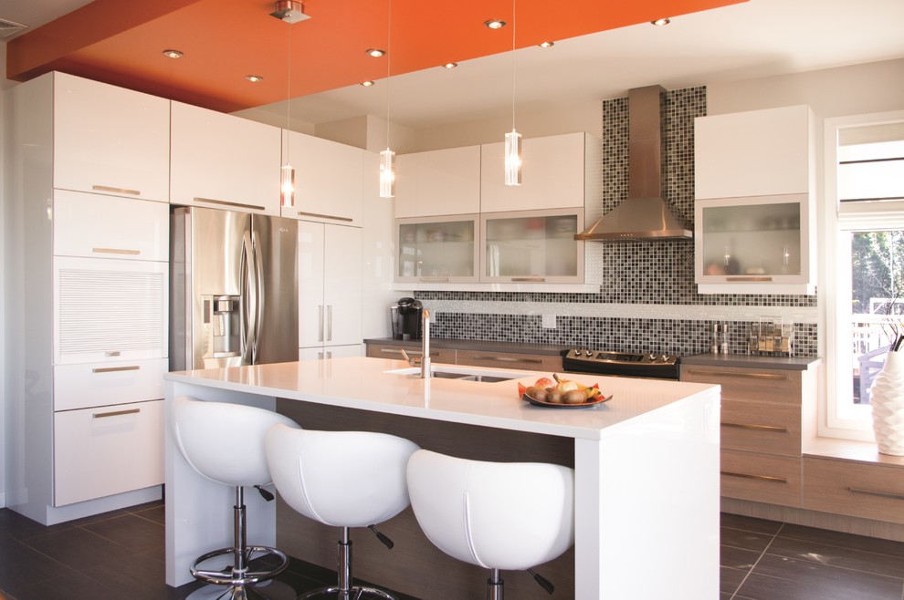 This is an example of a mid-sized contemporary l-shaped eat-in kitchen in Montreal with a double-bowl sink, flat-panel cabinets, white cabinets, granite benchtops, grey splashback, ceramic splashback, stainless steel appliances, ceramic floors and with island.