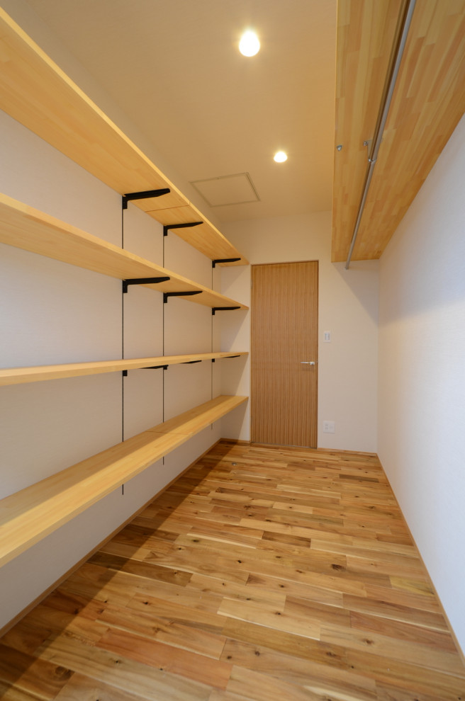 Mid-sized modern gender-neutral walk-in wardrobe in Other with medium hardwood floors and wallpaper.
