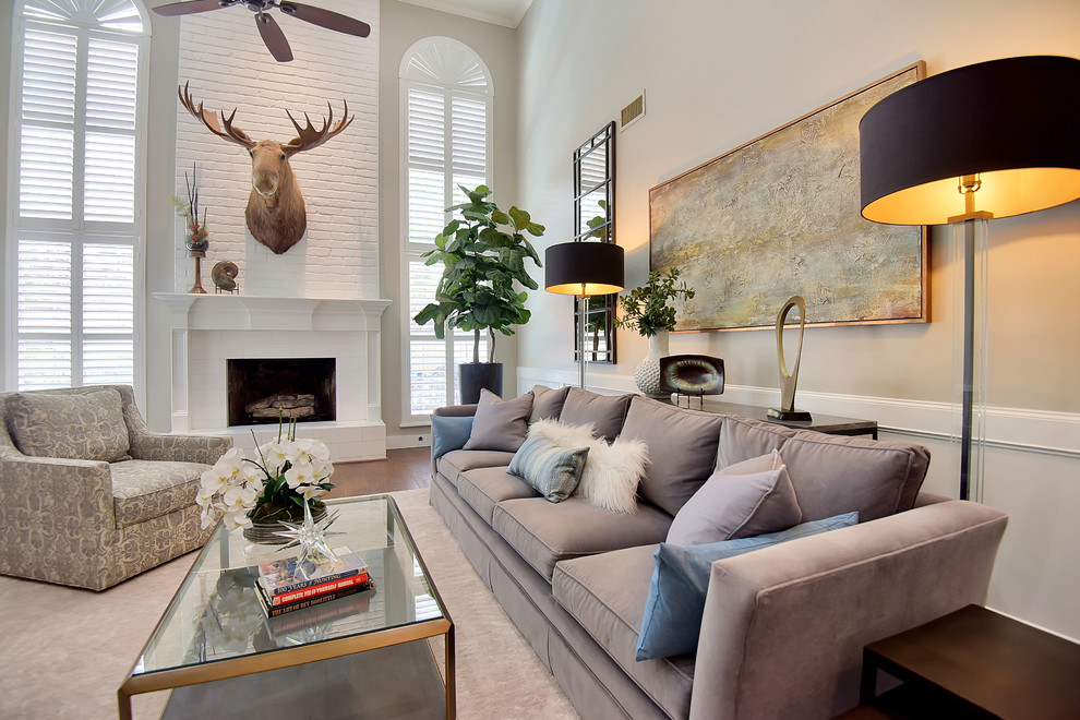 Inspiration for a mid-sized transitional formal enclosed living room in Tampa with grey walls, medium hardwood floors, a standard fireplace, a plaster fireplace surround, no tv and brown floor.