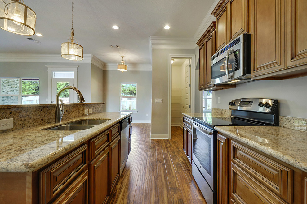 Inspiration for a large transitional l-shaped medium tone wood floor open concept kitchen remodel with an undermount sink, raised-panel cabinets, medium tone wood cabinets, granite countertops, stainless steel appliances and an island