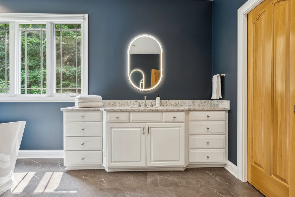 This is an example of a medium sized traditional bathroom in Columbus with raised-panel cabinets, white cabinets, a freestanding bath, a double shower, white tiles, vinyl flooring, grey floors, a hinged door, white worktops, a wall niche, double sinks and a built in vanity unit.