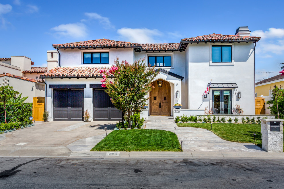 Photo of a mediterranean two-storey white house exterior in Orange County with a hip roof and a tile roof.