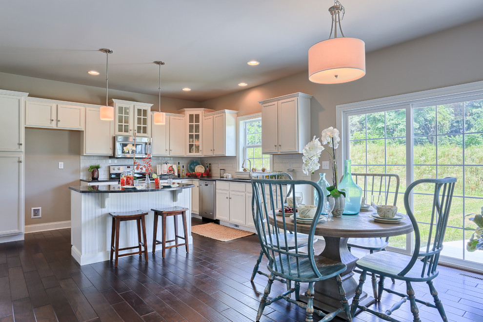 Inspiration for a large transitional l-shaped dark wood floor eat-in kitchen remodel with recessed-panel cabinets, white cabinets, granite countertops, white backsplash, ceramic backsplash, stainless steel appliances and an island