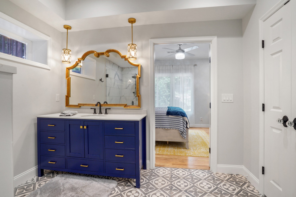 Medium sized classic ensuite bathroom in Atlanta with blue cabinets, a built-in shower, multi-coloured tiles, porcelain tiles, porcelain flooring, engineered stone worktops, grey floors, a hinged door, white worktops, a single sink and a freestanding vanity unit.