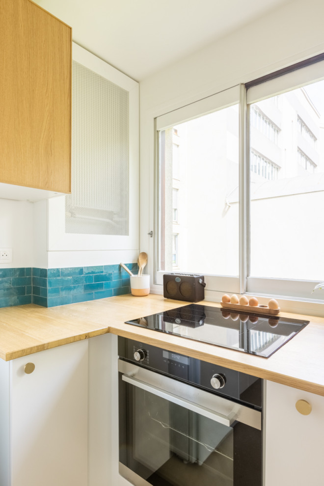 Large contemporary u-shaped open plan kitchen in Paris with a submerged sink, light wood cabinets, wood worktops, blue splashback, ceramic splashback, concrete flooring and beige floors.