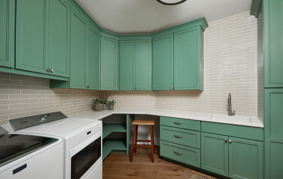 Design ideas for a traditional l-shaped dedicated laundry room in Grand Rapids with an undermount sink, shaker cabinets, green cabinets, quartz benchtops, medium hardwood floors, a side-by-side washer and dryer, brown floor and white benchtop.