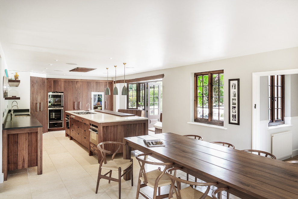This is an example of a mid-sized traditional eat-in kitchen in Hampshire with an undermount sink, flat-panel cabinets, medium wood cabinets, stainless steel appliances, with island and limestone floors.
