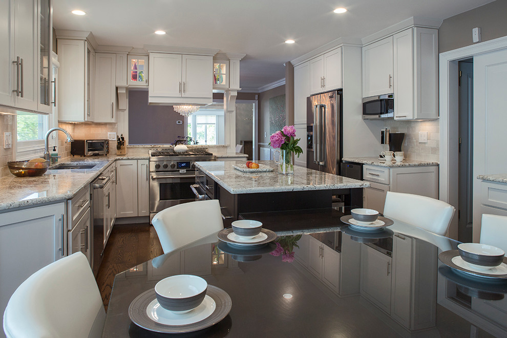 Large transitional galley dark wood floor eat-in kitchen photo with an undermount sink, shaker cabinets, white cabinets, granite countertops, beige backsplash, stone tile backsplash, stainless steel appliances, brown walls and an island