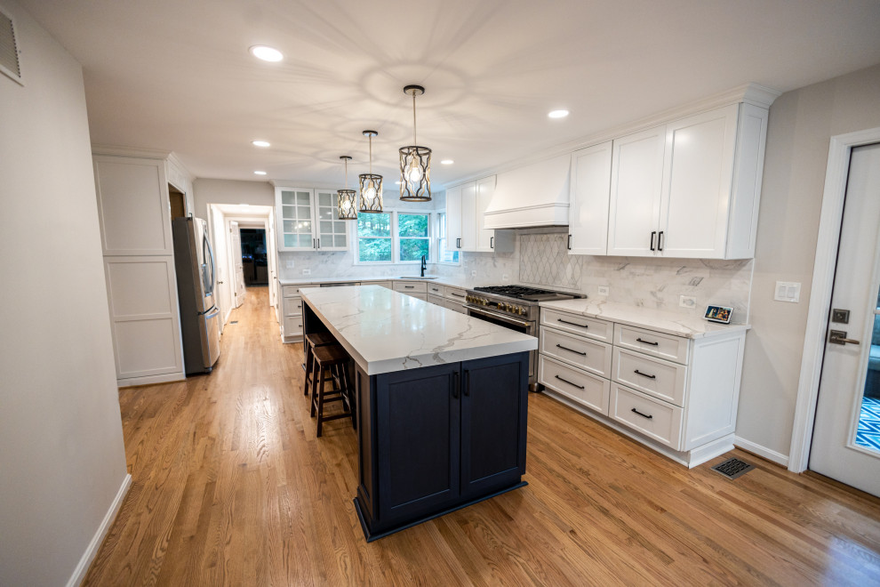 Eat-in kitchen - large transitional l-shaped light wood floor and brown floor eat-in kitchen idea in Baltimore with an undermount sink, shaker cabinets, white cabinets, quartz countertops, white backsplash, marble backsplash, stainless steel appliances, an island and white countertops