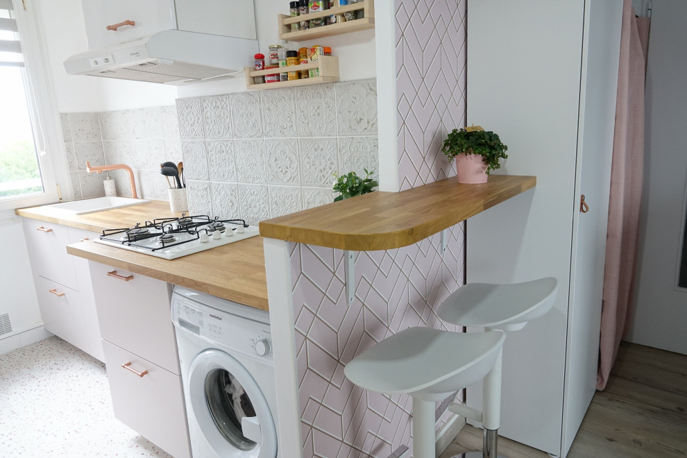 Photo of a mid-sized modern galley eat-in kitchen in Other with an undermount sink, beaded inset cabinets, pink cabinets, wood benchtops, white splashback, ceramic splashback, white appliances, terrazzo floors, a peninsula, beige floor and beige benchtop.