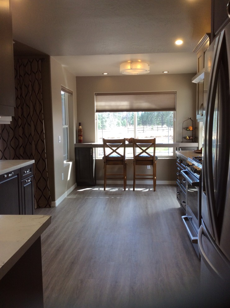 Mid-sized transitional dark wood floor and brown floor eat-in kitchen photo in Phoenix with a single-bowl sink, raised-panel cabinets, dark wood cabinets, onyx countertops, brown backsplash, ceramic backsplash, stainless steel appliances and an island