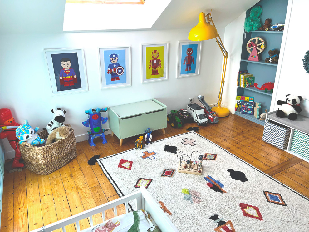 Medium sized contemporary nursery for boys in Paris with white walls and light hardwood flooring.
