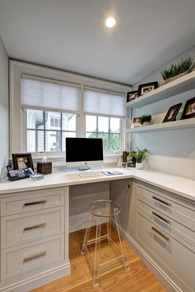 Small beach style home office in New York with grey walls, light hardwood floors, a built-in desk and brown floor.