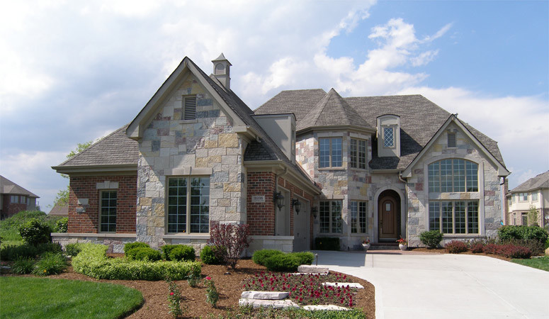 This is an example of a large traditional two-storey grey exterior in Chicago with stone veneer and a hip roof.