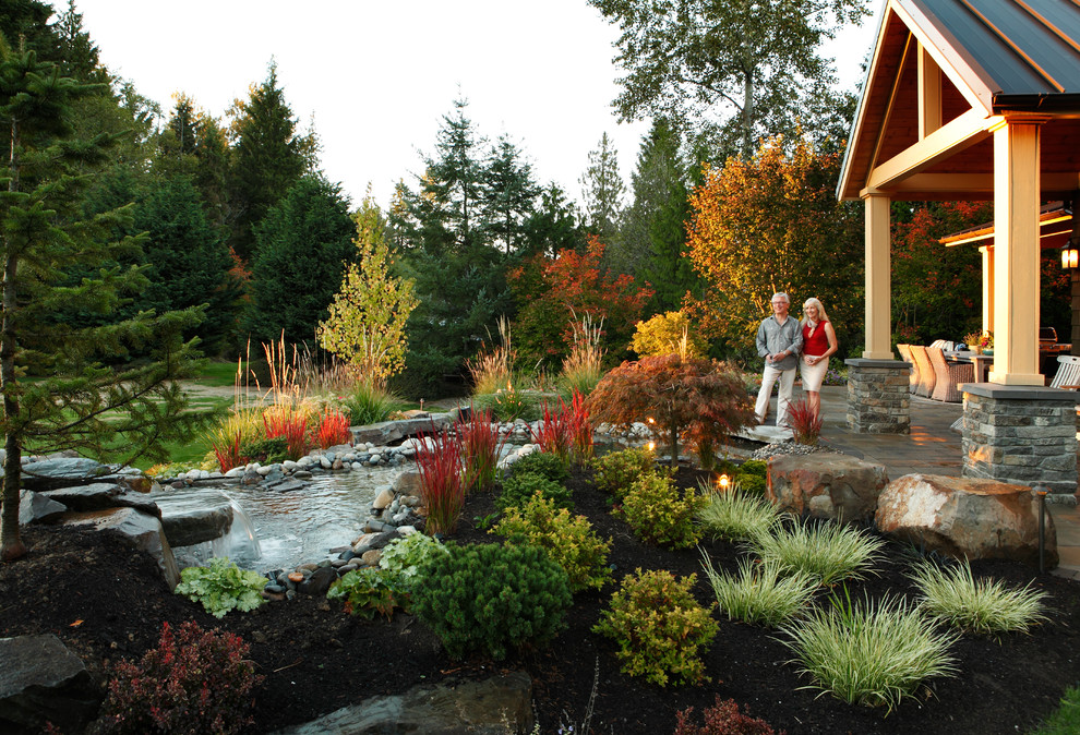 Photo of a large backyard full sun formal garden in Seattle with a water feature and natural stone pavers.