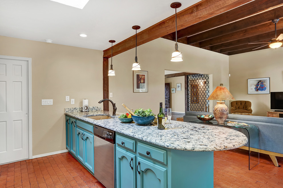 Mid-sized traditional galley open plan kitchen in Albuquerque with an undermount sink, recessed-panel cabinets, turquoise cabinets, quartz benchtops, stainless steel appliances, brick floors and with island.
