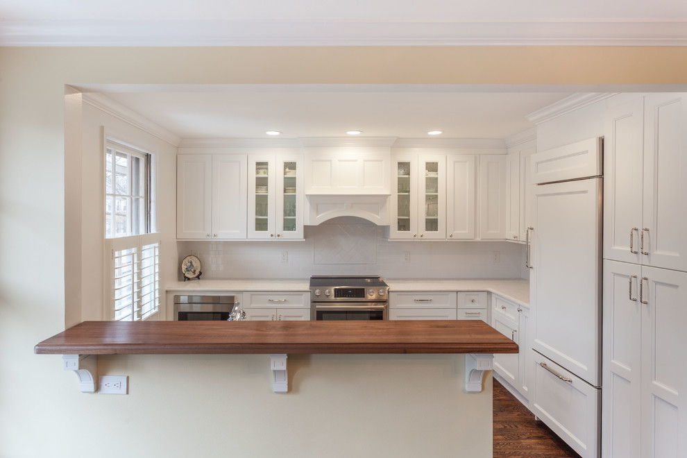 This is an example of a medium sized classic l-shaped kitchen/diner in DC Metro with shaker cabinets, white cabinets, engineered stone countertops, ceramic splashback, stainless steel appliances, medium hardwood flooring, brown floors and white worktops.