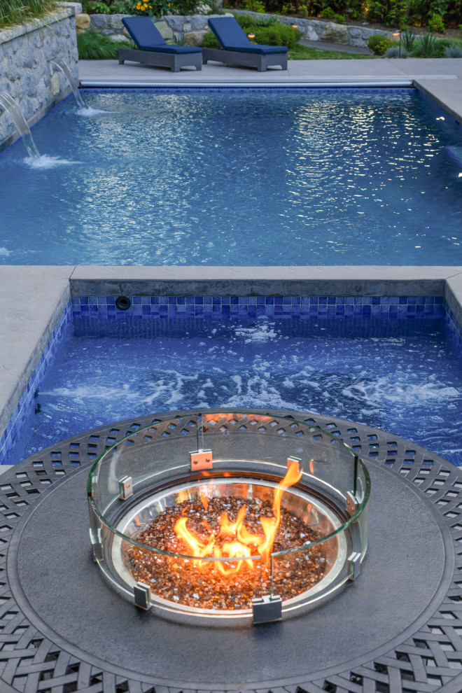 This is an example of an arts and crafts backyard rectangular pool in Vancouver with a hot tub and concrete pavers.