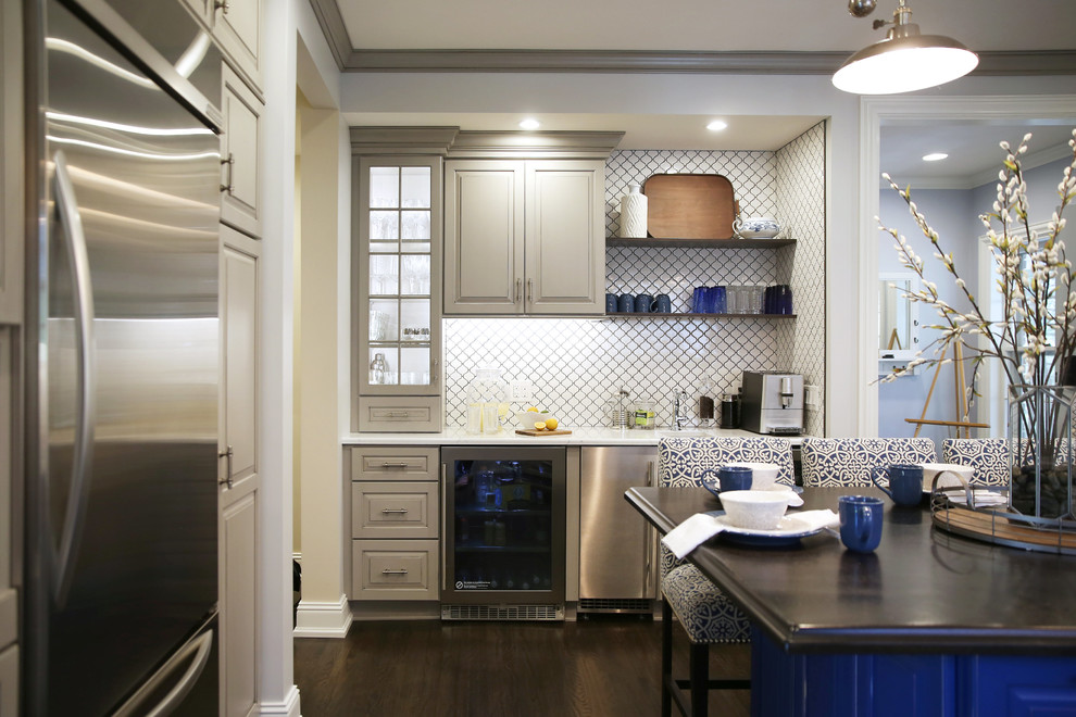 Large transitional l-shaped dark wood floor and brown floor enclosed kitchen photo with raised-panel cabinets, white backsplash, ceramic backsplash, stainless steel appliances and an island