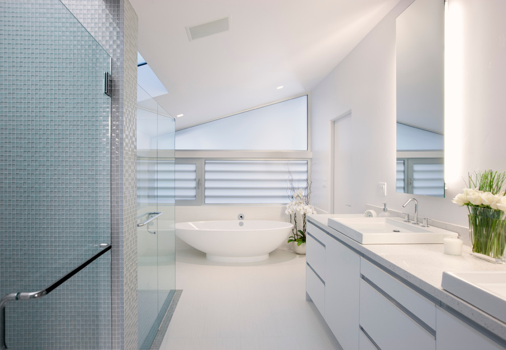 Design ideas for a midcentury bathroom in Santa Barbara with flat-panel cabinets, white cabinets, a freestanding tub, gray tile and white walls.