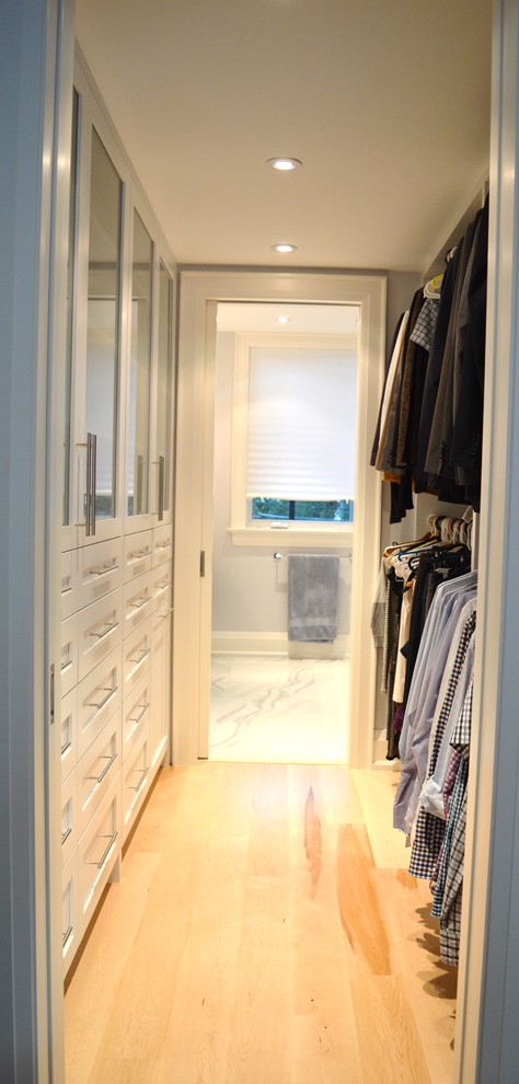 This is an example of a large arts and crafts gender-neutral walk-in wardrobe in Toronto with shaker cabinets, white cabinets and light hardwood floors.