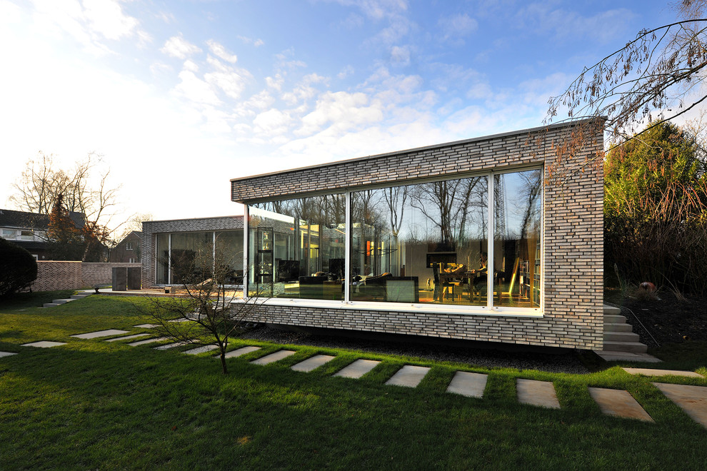 Expansive contemporary one-storey brick grey house exterior in Other with a flat roof.